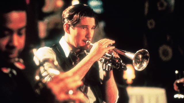 Richard Gere spielt im hochgekrempelten Hemd Trompete. Richard Gere spielt im hochgekrempelten Hemd Trompete.