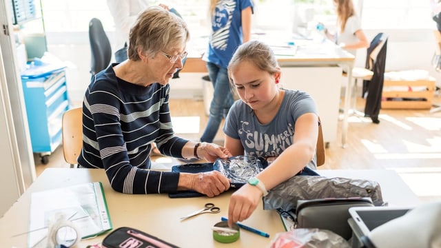 Ältere Frau hilft Mädchen bei der Handarbeit Ältere Frau hilft Mädchen bei der Handarbeit