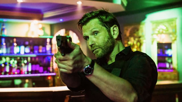 Ein Mann in einer Bar, der eine Pistole hält Ein Mann in einer Bar, der eine Pistole hält