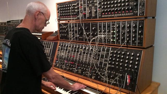 Ein Mann steht ein einem Synthesizer Ein Mann steht ein einem Synthesizer