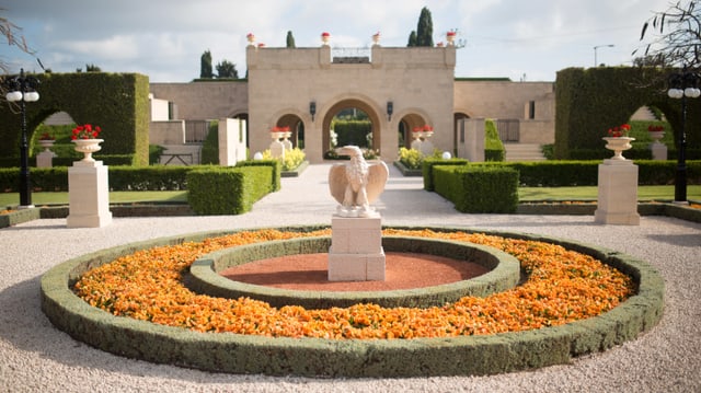 Ein weisses Gebäude, davor ist ein schöner Garten mit der Statue eines Adlers. Ein weisses Gebäude, davor ist ein schöner Garten mit der Statue eines Adlers.