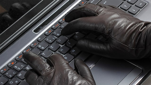 Hand mit Handschuhen auf einer Computer-Tastatur. Hand mit Handschuhen auf einer Computer-Tastatur.