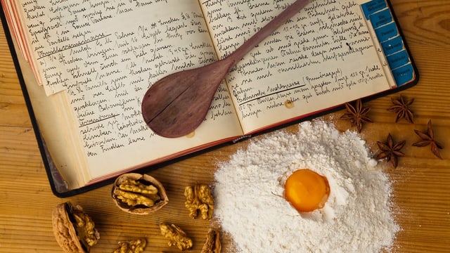 Ein Kochlöffel auf einem aufgeschlagenen Kochbuch mit handgeschriebenen Rezepten. Ein Kochlöffel auf einem aufgeschlagenen Kochbuch mit handgeschriebenen Rezepten.