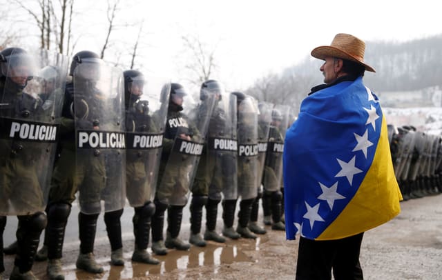 Eingehüllt in die Flagge Bosnien-Herzegovinas steht ein demonstrierender Veteran der Übermacht der Polizei gegenüber. Eingehüllt in die Flagge Bosnien-Herzegovinas steht ein demonstrierender Veteran der Übermacht der Polizei gegenüber.