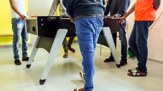 Asylbewerber stehen um einen Tischfussballkasten herum Asylbewerber stehen um einen Tischfussballkasten herum