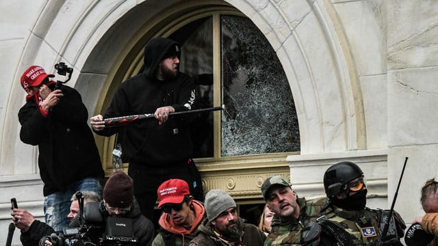Ein Trump-Supporter schlägt beim Sturm aufs Kapitol ein Fenster mit einem Baseballschläger ein. Ein Trump-Supporter schlägt beim Sturm aufs Kapitol ein Fenster mit einem Baseballschläger ein.