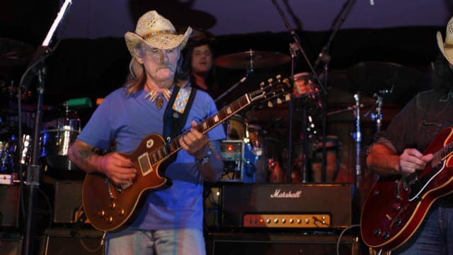 Dickey Betts spielt Gitarre während eines Konzerts. Dickey Betts spielt Gitarre während eines Konzerts.