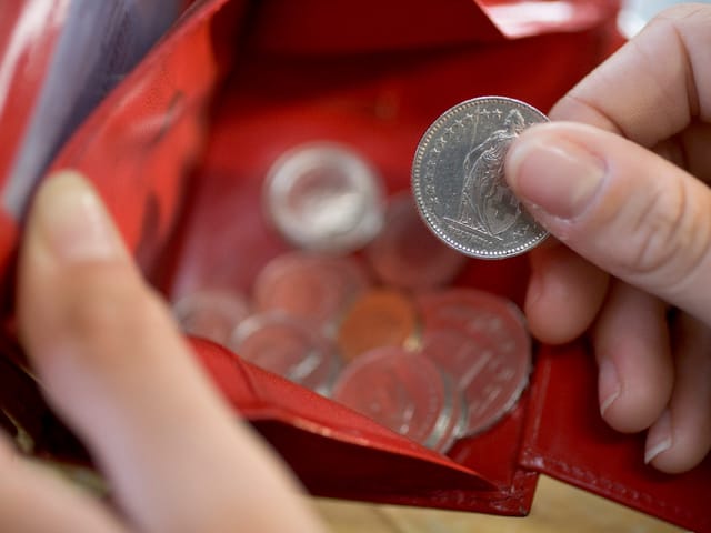 Hand nimmt Zweifränkler aus einem Portemonnaie.