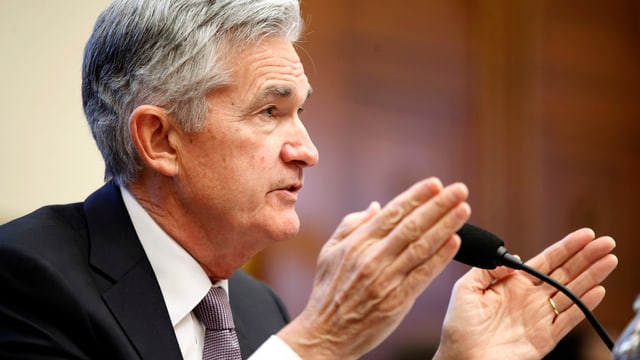 Jerome Powell spricht und gestikuliert mit den Händen vor einem Mikrofon Jerome Powell spricht und gestikuliert mit den Händen vor einem Mikrofon