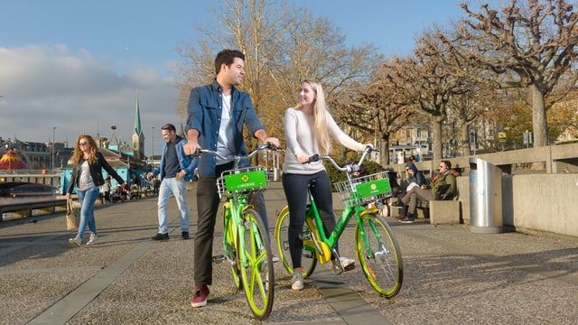 Zwei Velofahrende auf grünen Limebike-Velo Zwei Velofahrende auf grünen Limebike-Velo