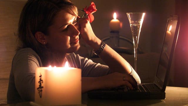 Eine Frau sitz mit Kerzen vor dem Computer Eine Frau sitz mit Kerzen vor dem Computer