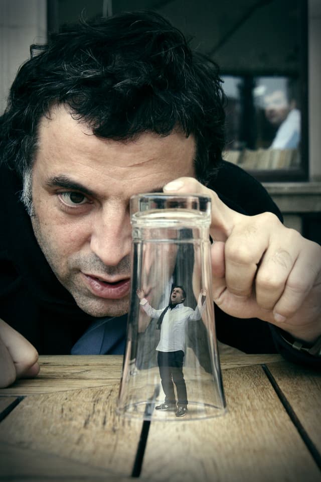 Keret beobachtet sich selber in Miniatur unter einem Wasserglas. Keret beobachtet sich selber in Miniatur unter einem Wasserglas.