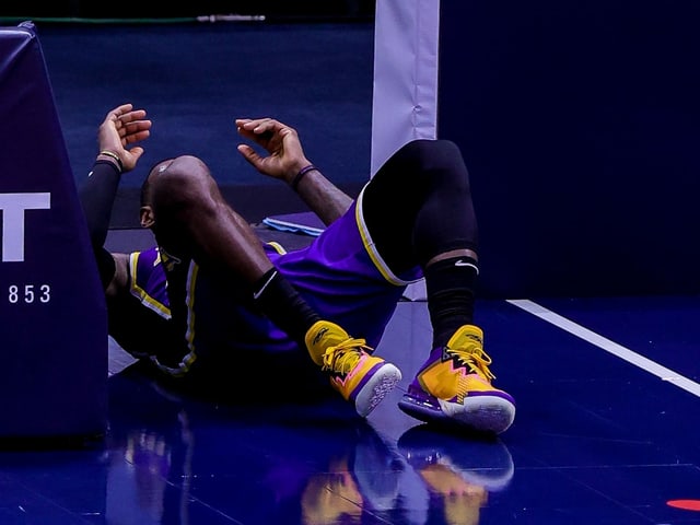 LeBron James liegt auf dem Rücken auf dem Hallenboden. LeBron James liegt auf dem Rücken auf dem Hallenboden.