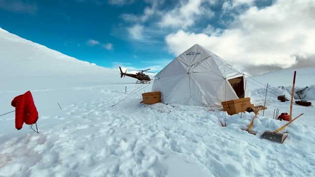 Zelt auf einer Eisfläche. Im Hintergrund ein Helikopter. Zelt auf einer Eisfläche. Im Hintergrund ein Helikopter.