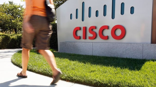 Frau läuft vor dem Logo der Firma Cisco vorbei. Frau läuft vor dem Logo der Firma Cisco vorbei.
