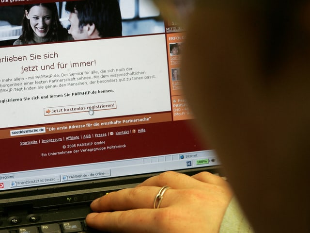 Eine Person sucht am Computer auf einer Vermittlungsplattform nach einem passenden Partner. Eine Person sucht am Computer auf einer Vermittlungsplattform nach einem passenden Partner.