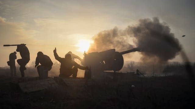 Symbolbild: Ukrainische Soldaten feuern im Gegenlicht eine Kanone ab. Symbolbild: Ukrainische Soldaten feuern im Gegenlicht eine Kanone ab.