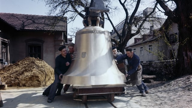 Männer bewegen grosse Glocke auf Wagen auf Schienen. Männer bewegen grosse Glocke auf Wagen auf Schienen.