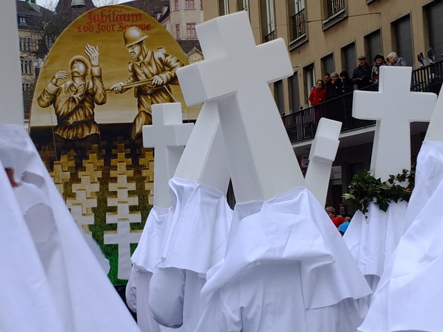 Clique mit weissen Kreuzen, auf der Laterne ersticht ein Soldat einen anderen.