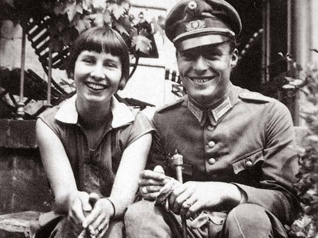 Historisches Foto: Eine junge Frau und ein junger Mann posieren lachend nebeneinander. Er trägt eine Soldatenuniform. Historisches Foto: Eine junge Frau und ein junger Mann posieren lachend nebeneinander. Er trägt eine Soldatenuniform.
