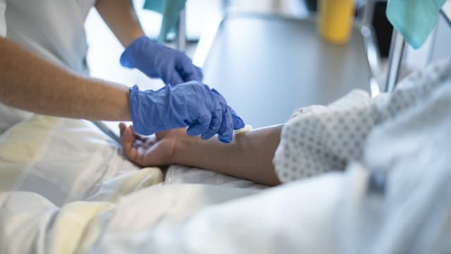 Hand mit Desinfektionshandschuhen tupft einen Unterarm. Hand mit Desinfektionshandschuhen tupft einen Unterarm.