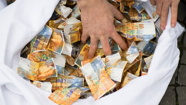 Symbolbild: Hand in einem Sack mit 10-Franken-Noten. Symbolbild: Hand in einem Sack mit 10-Franken-Noten.