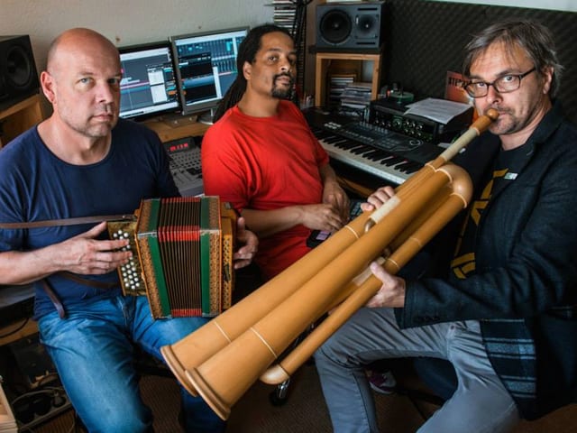Drei Männer spielen auf ihren Instrumenten: Ein Alphorn, ein Örgeli und ein Keyboard. Drei Männer spielen auf ihren Instrumenten: Ein Alphorn, ein Örgeli und ein Keyboard.