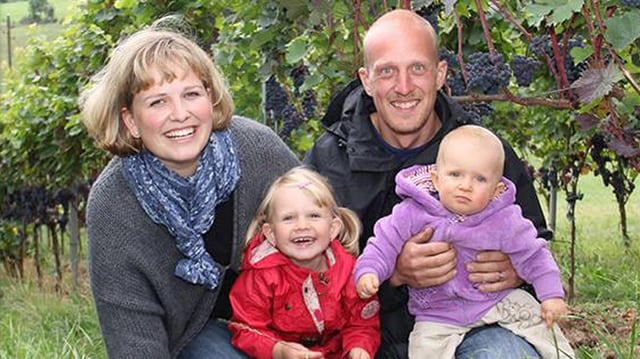 Familie mit zwei Kindern vor Rebstöcken. Familie mit zwei Kindern vor Rebstöcken.
