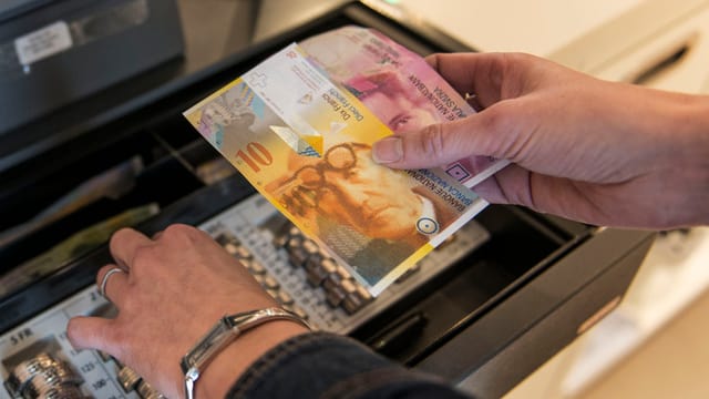 Eine Frau steht an der Kasse und hantiert mit Geld. Eine Frau steht an der Kasse und hantiert mit Geld.