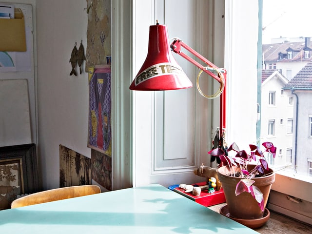 Tisch und rote Tischlampe, die auf dem Fenstersims einer Altbauwohnung steht. Tisch und rote Tischlampe, die auf dem Fenstersims einer Altbauwohnung steht.
