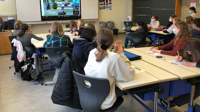 Schülerinnen und Schüler blicken in einem Klassenzimmer auf eine Leinwand Schülerinnen und Schüler blicken in einem Klassenzimmer auf eine Leinwand