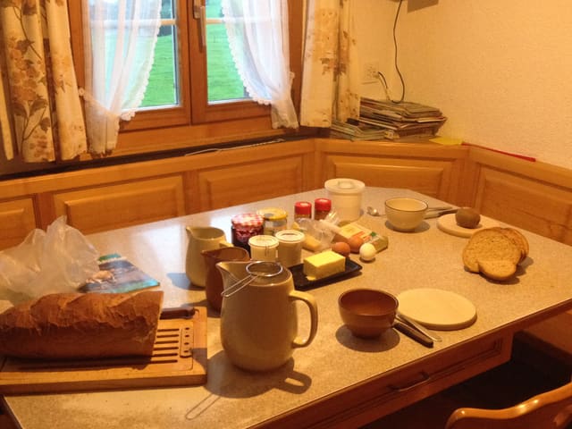 Brot, Kanne mit Milch, Butter, Ei, Konfitüre.