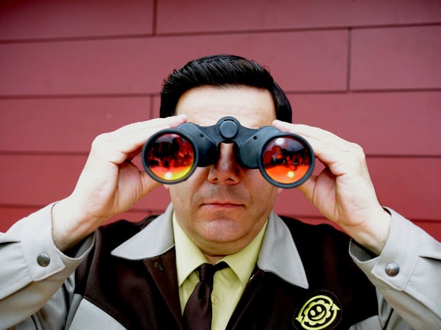 Bruno Cathomas als Müllinspektor Hansjörg Stähli blickt durch ein Fernglas, Bruno Cathomas als Müllinspektor Hansjörg Stähli blickt durch ein Fernglas,