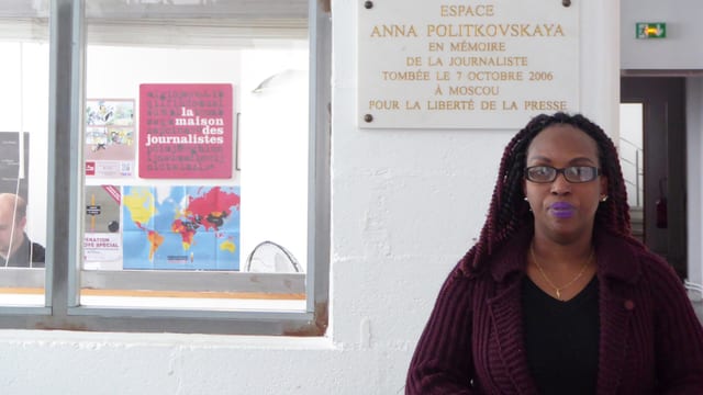 Elyse Ngabire steht vor einem Büro. Elyse Ngabire steht vor einem Büro.