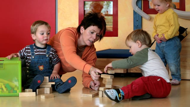 Eine Frau spielt mit Kindern am Boden Eine Frau spielt mit Kindern am Boden