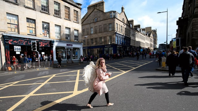 Eine Frau, die als Engel verkleidet ist, läuft in Edinburg über die Strasse. Eine Frau, die als Engel verkleidet ist, läuft in Edinburg über die Strasse.