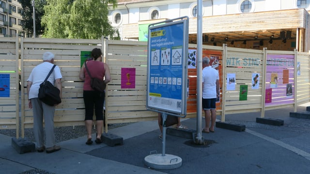 Eine Holzwand vor dem Luzerner Theater mit Gucklöchern, durch welche Menschen schauen. Eine Holzwand vor dem Luzerner Theater mit Gucklöchern, durch welche Menschen schauen.