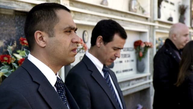 Jovan und José stehen vor einer Grabplatte mit Blumen. Jovan und José stehen vor einer Grabplatte mit Blumen.