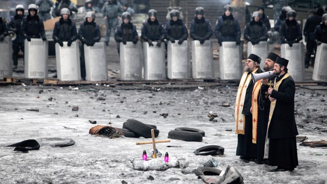 Priester, im Hintergrund Polizisten, während der Ausschreitungen in Kiew im vergangenen Februar. Priester, im Hintergrund Polizisten, während der Ausschreitungen in Kiew im vergangenen Februar.