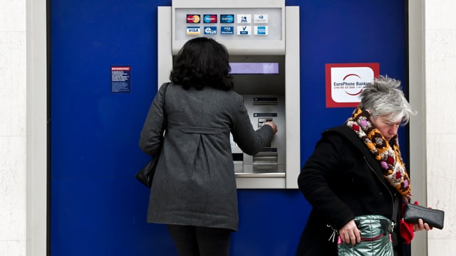 Eine Frau hebt an einem Bankomat Geld ab