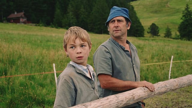 Ein Bub und sein Vater stehen an einem Zaun. Ein Bub und sein Vater stehen an einem Zaun.