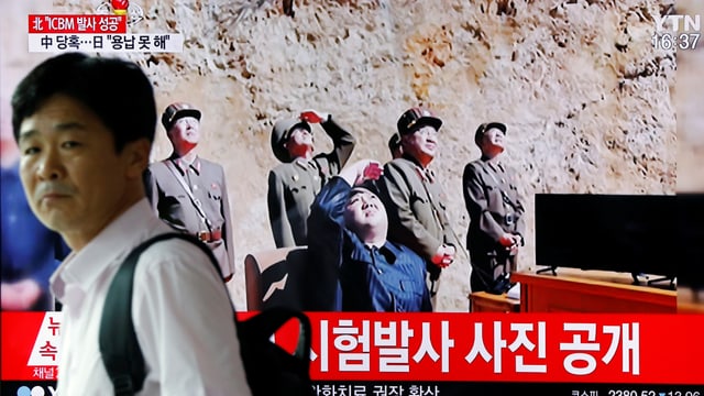 Ein Bildschirm zeigt Kim Jong Un und nordkoreanische Militärs, die nach oben schauen. Ein Bildschirm zeigt Kim Jong Un und nordkoreanische Militärs, die nach oben schauen.