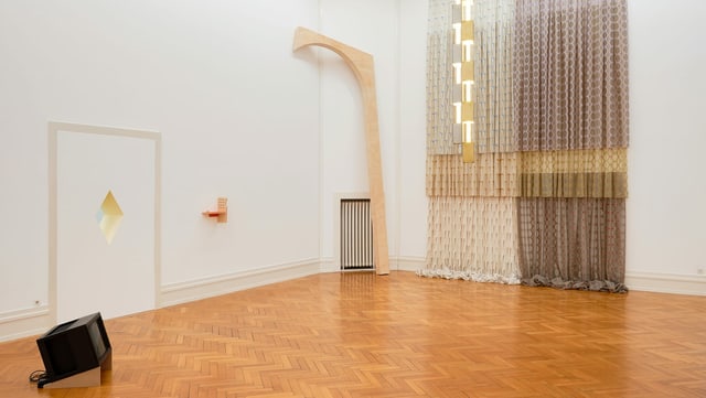 Blick in einen Raum, in dem auf dem Fussboden ein Fernseher steht und in dem an der Wand Vorhänge hängen. Blick in einen Raum, in dem auf dem Fussboden ein Fernseher steht und in dem an der Wand Vorhänge hängen.
