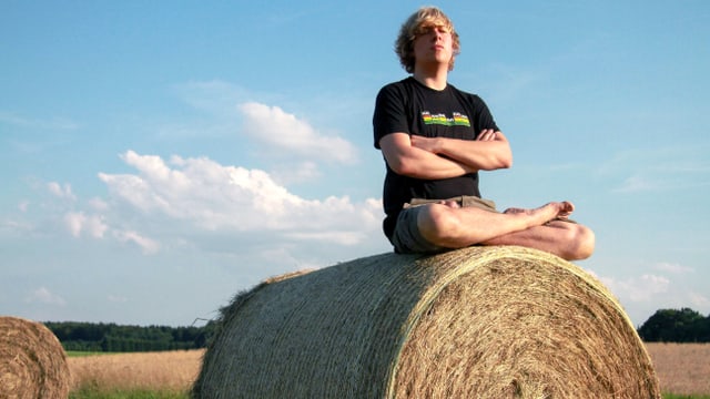 Ein junger Mann sitzt auf einem Heuballen. Ein junger Mann sitzt auf einem Heuballen.