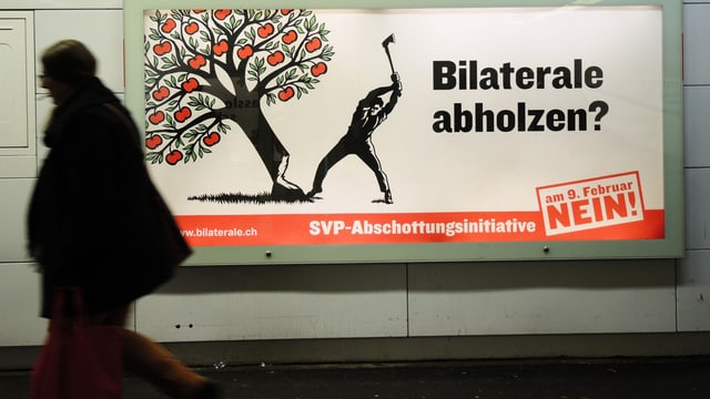 Person geht an einem Abstimmungsplakat vorbei. Person geht an einem Abstimmungsplakat vorbei.