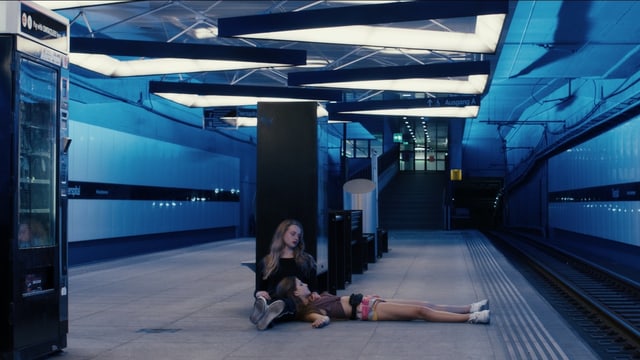 Zwei Mädchen am Boden in einem unterirdischen Bahnhof. Zwei Mädchen am Boden in einem unterirdischen Bahnhof.