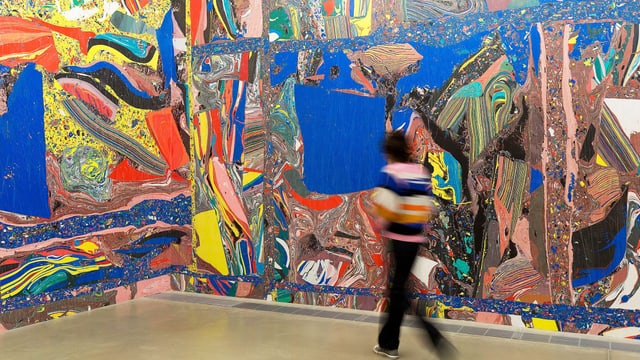 Eine Museumsbesucherin läuft durch einen bunten Raum. Eine Museumsbesucherin läuft durch einen bunten Raum.