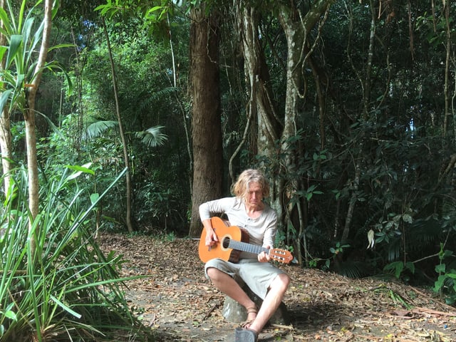 Jogl sitzt mit Gitarre im Regenwald. Jogl sitzt mit Gitarre im Regenwald.