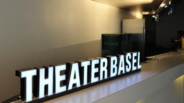Der beleuchtete Schriftzug «Theater Basel» vor einer hellen Wand Der beleuchtete Schriftzug «Theater Basel» vor einer hellen Wand