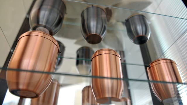 Mehrere Urnen aus Metall in einem Regal. Mehrere Urnen aus Metall in einem Regal.
